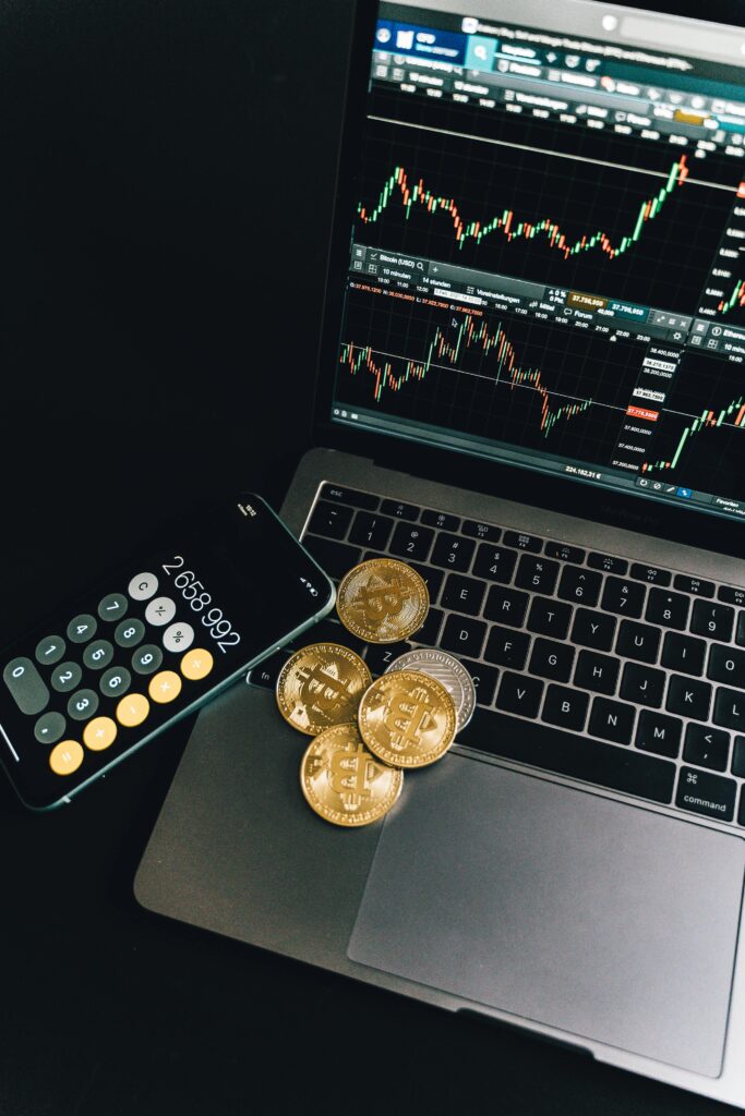 pexels photo 6780789 6780789 A still life of Bitcoin coins, a smartphone calculator, and a trading chart on a laptop.