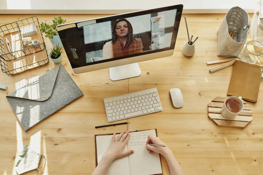 pexels photo 4145190 4145190 Person taking notes during a video call at a neatly organized home desk, showing remote work lifestyle.
