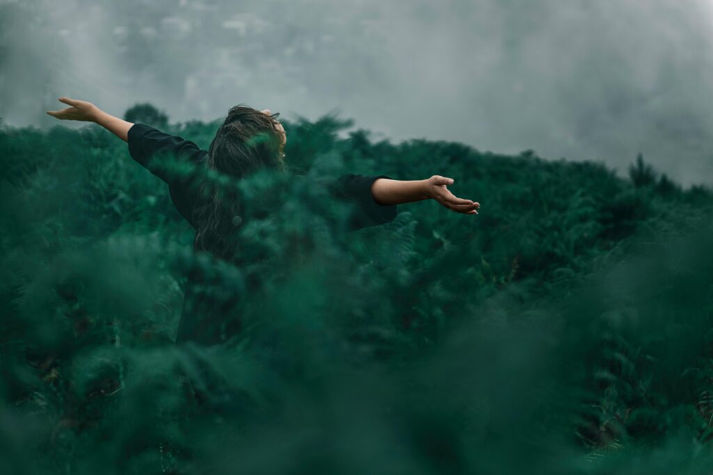 What Is the FIRE Movement A woman with open arms enjoying freedom in a foggy green landscape.